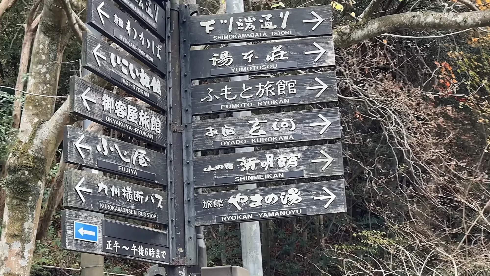 Wooden signpost in Kurokawa Onsen pointing to the Kyushu Odan bus stop and to several inns by name