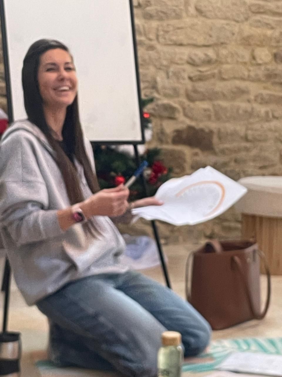 Woman practicing yoga warrior pose on a wooden platform surrounded by forested mountains in early morning light.