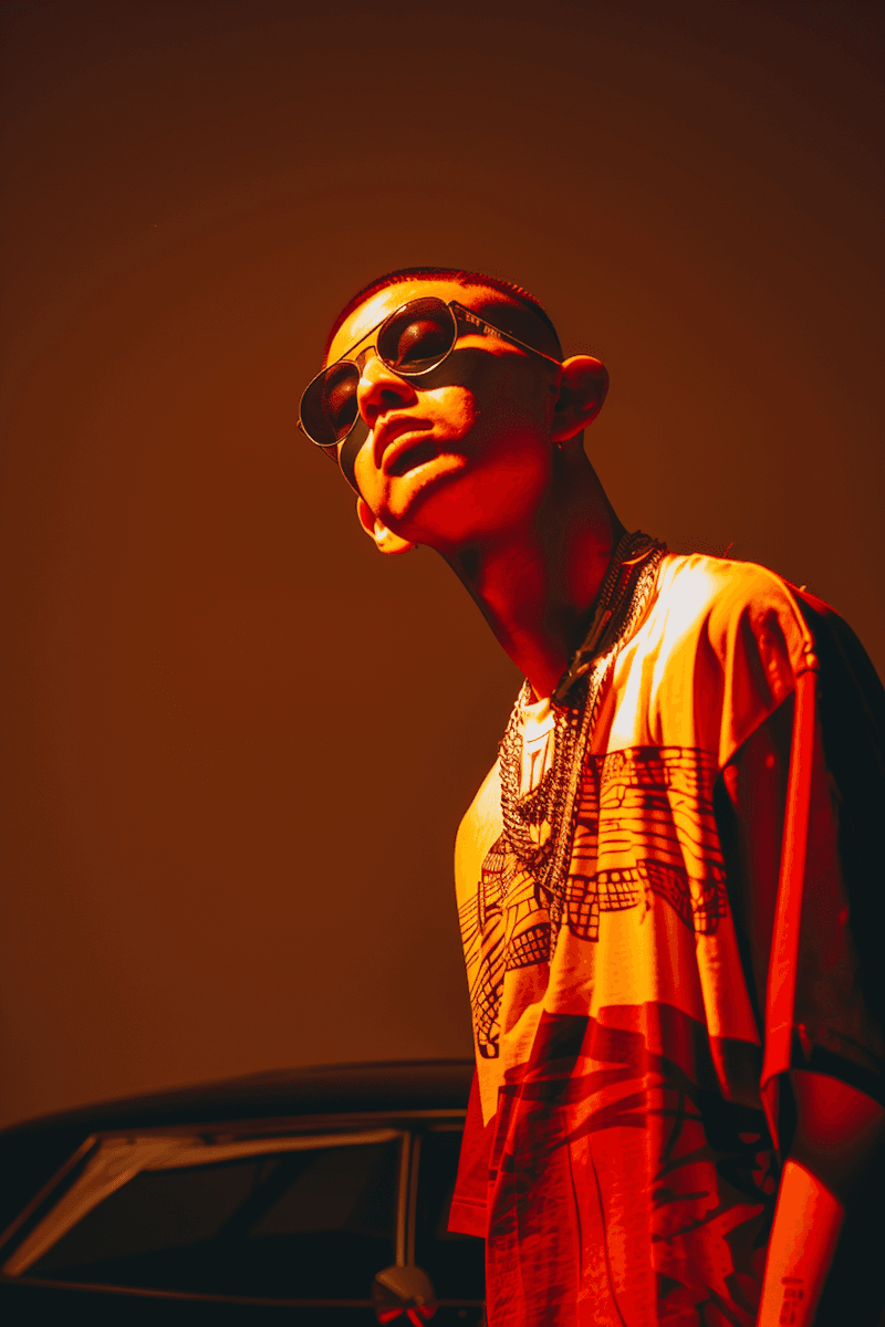 Low-angle portrait of a man in sunglasses under intense orange lighting