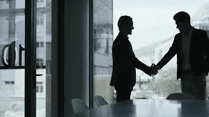 Zwei Geschäftsleute im Gegenlicht beim Handschlag in einem Büro als Sinnbild für den Ausstieg von GTCR bei Worldpay gegen Anteile an Global Payments.