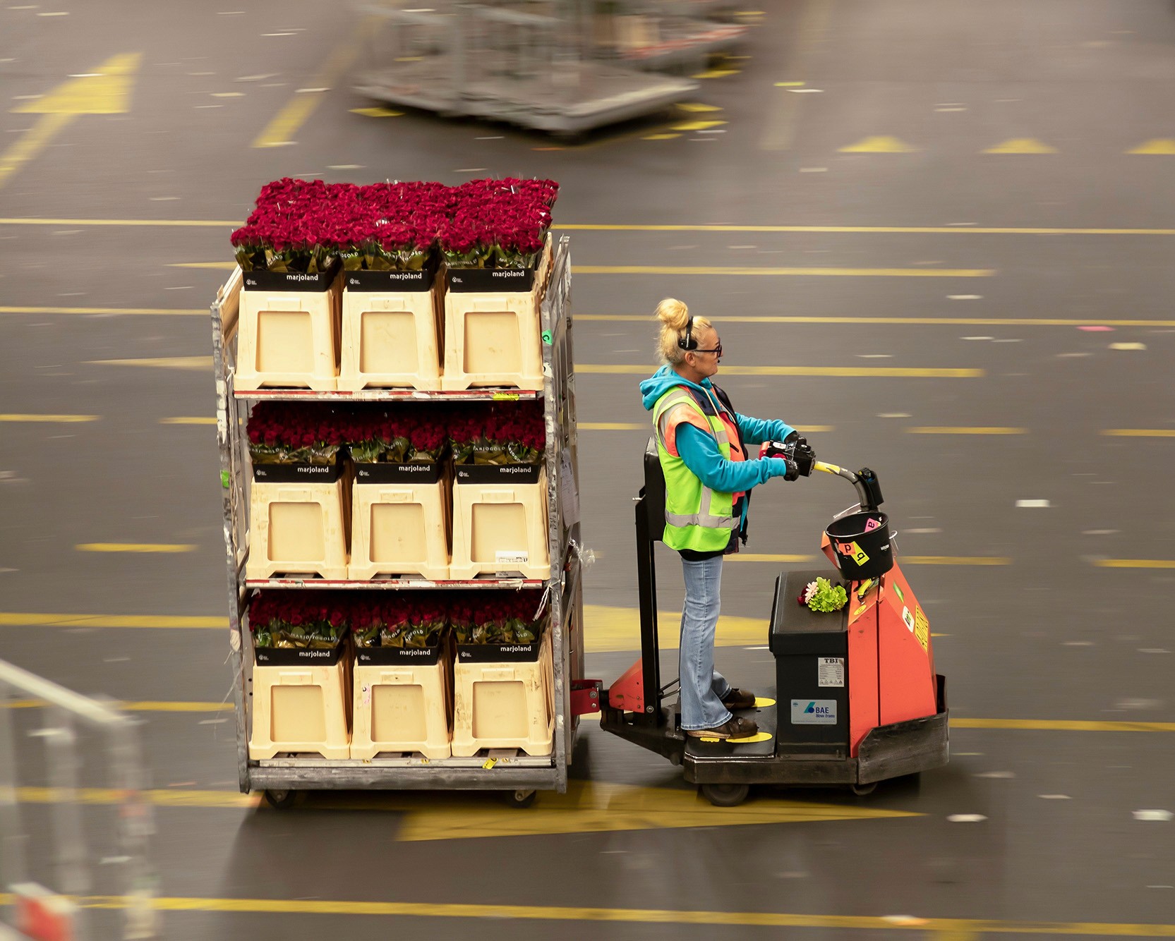 Woman operating an electric pump truck filled with flowers in crates