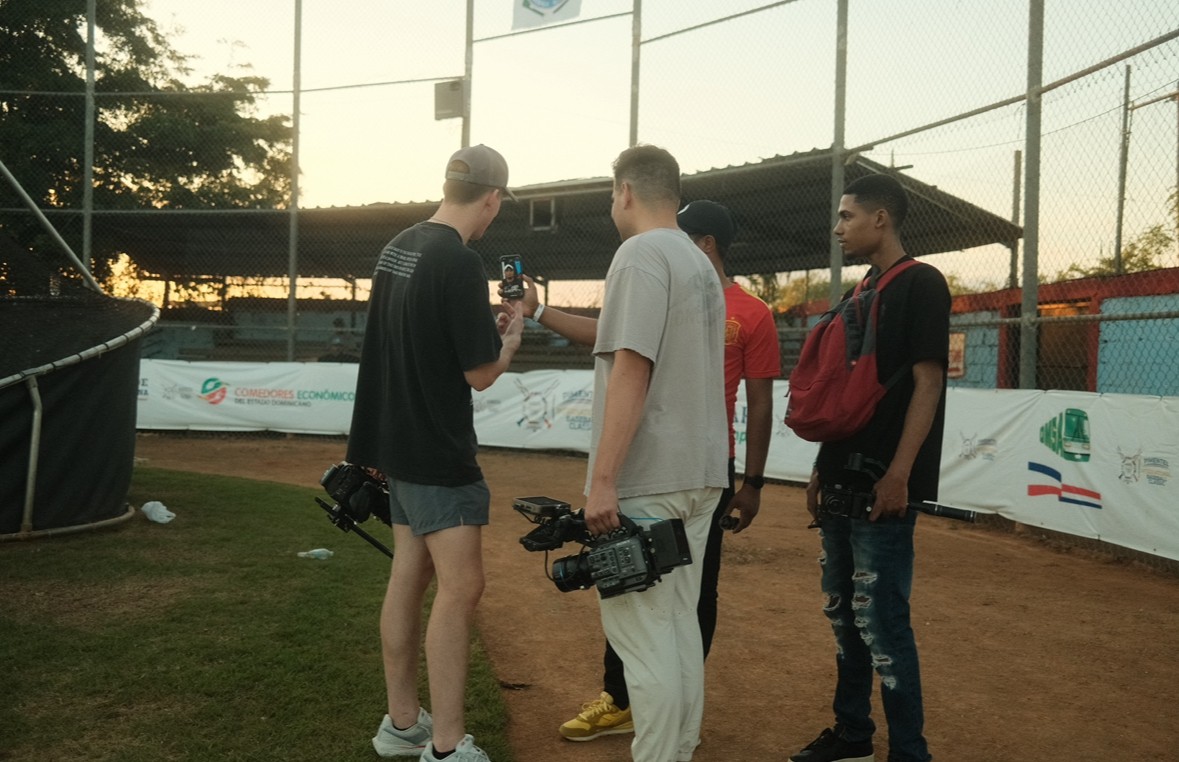 Black and white image of people working at a table with laptops, showing hands gesturing during discussion of digital content displayed on screens, with fabrica® logo in the corner.