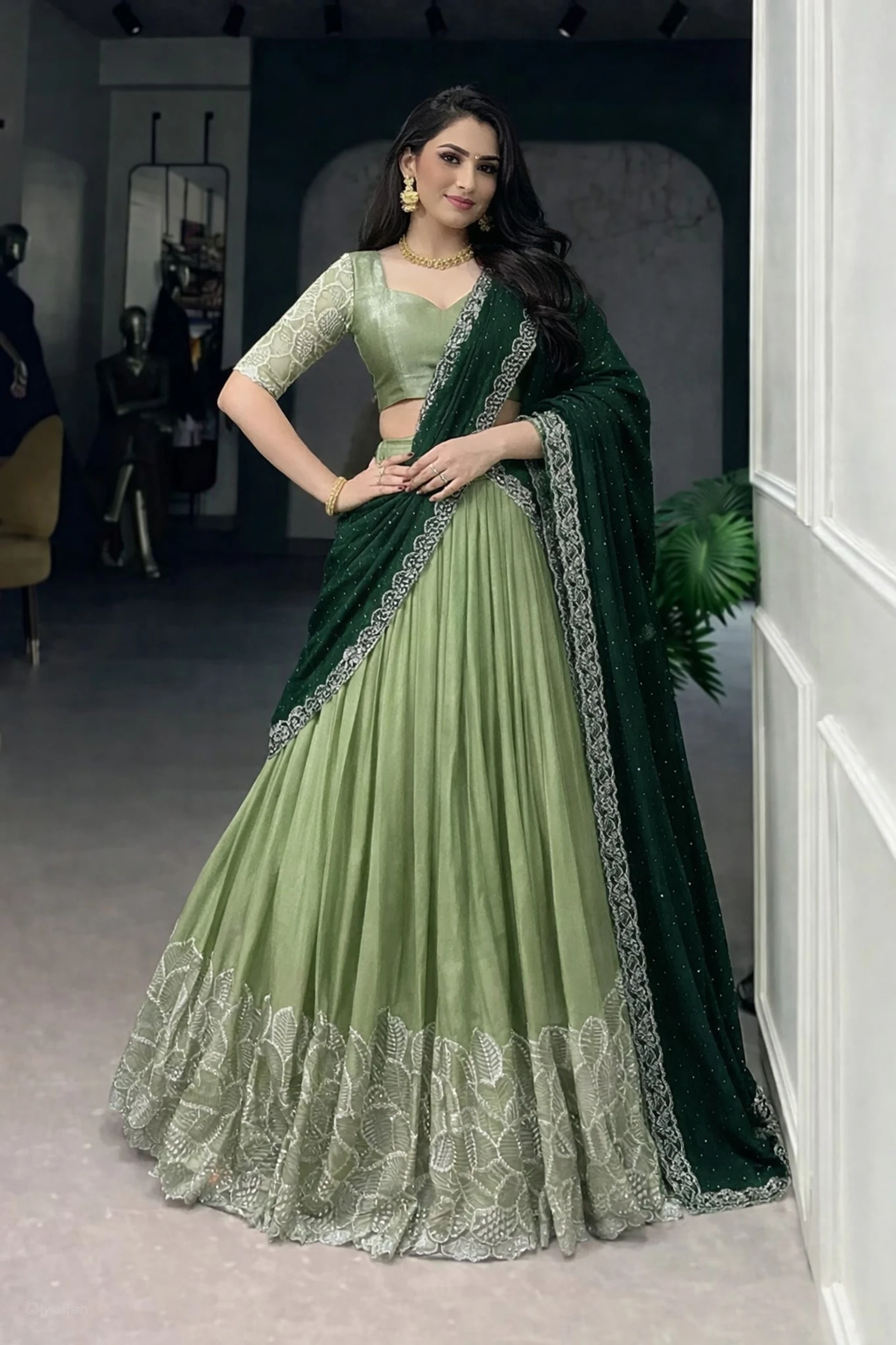 Woman in a sage green lehenga with a dark green dupatta