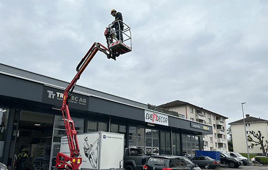 Four diverse professionals collaboratively working on a laptop, with one person pointing at the screen while others observe.