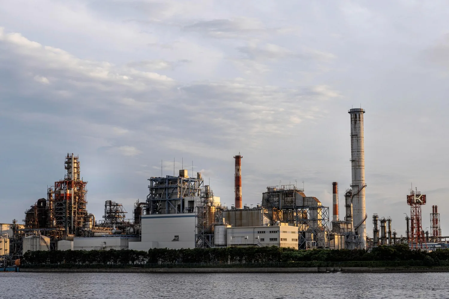 Industrial plant with tall chimneys beside the water at dusk