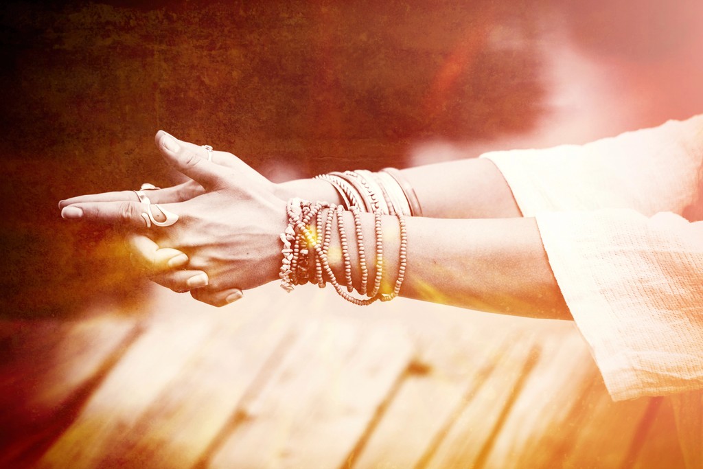 woman with hands in yoga mudra with bracelets