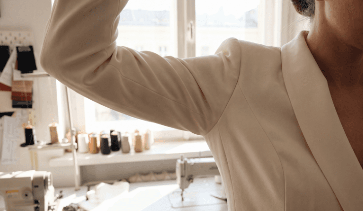 Tailored ivory wedding suit showing comfortable arm movement and fit during a bespoke suit fitting.