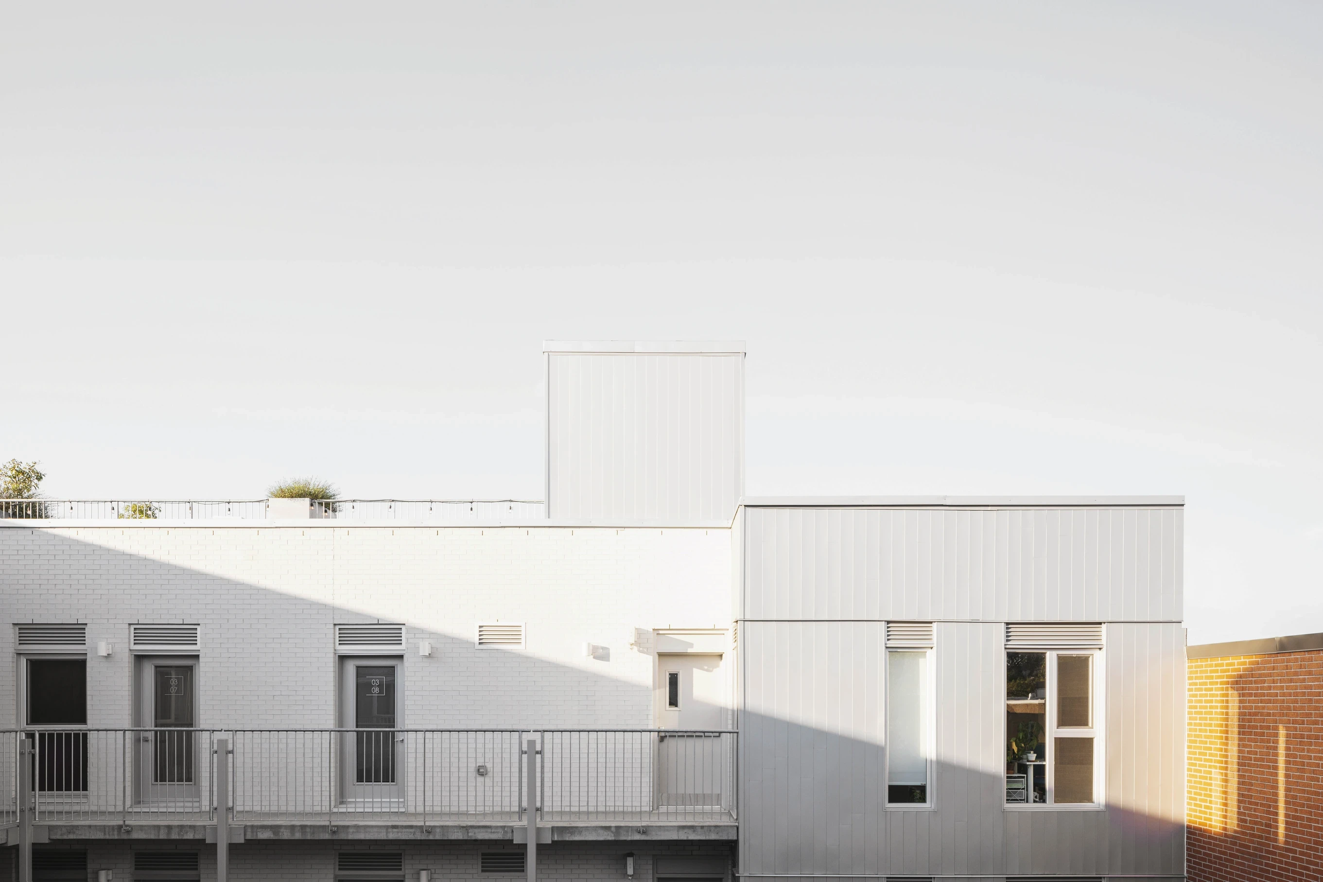 Façade arrière du bâtiment résidentiel Le Petit Laurier, volumes minimalistes et revêtement clair sous la lumière naturelle.