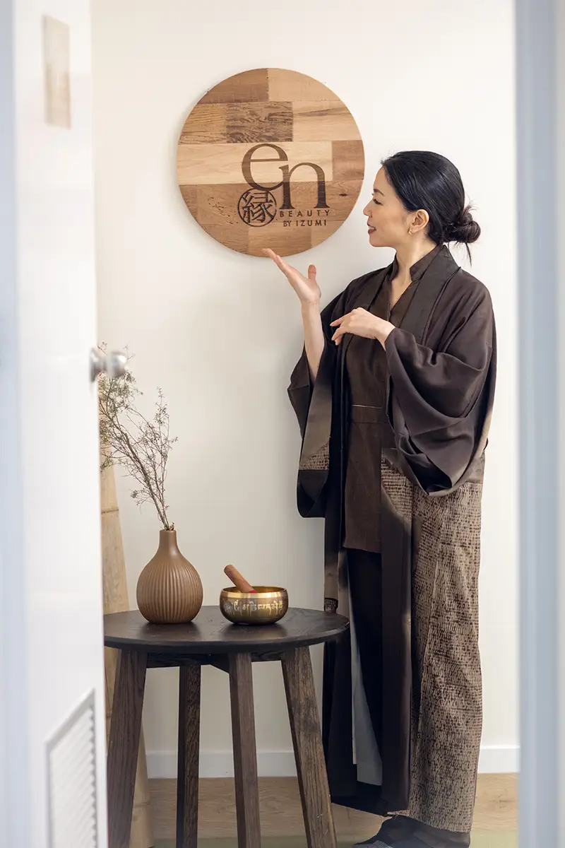 En Beauty owner points to the en beauty logo that has been laser printed on some traditional Japanese wood