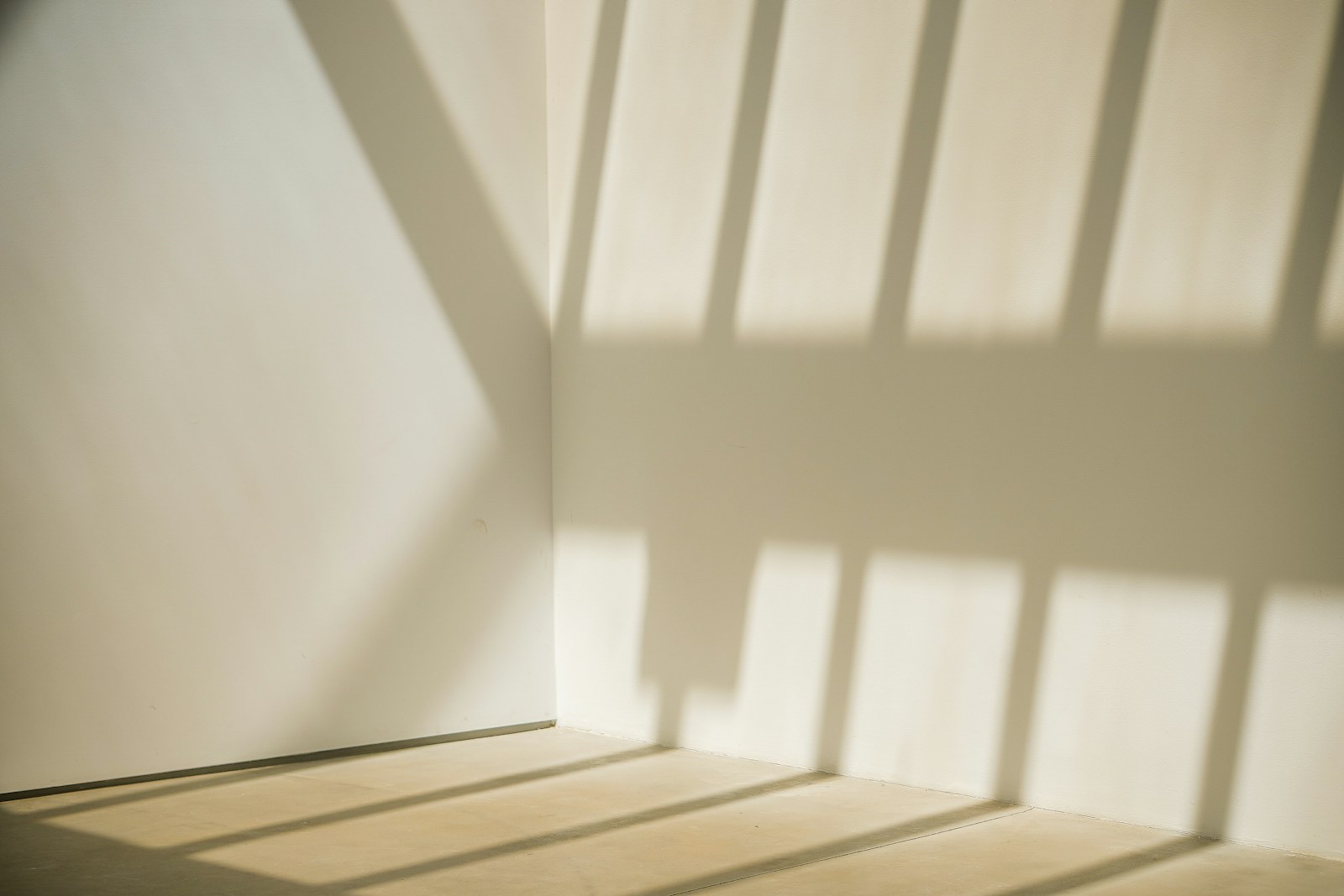 An empty room with slatted shadows across bare walls