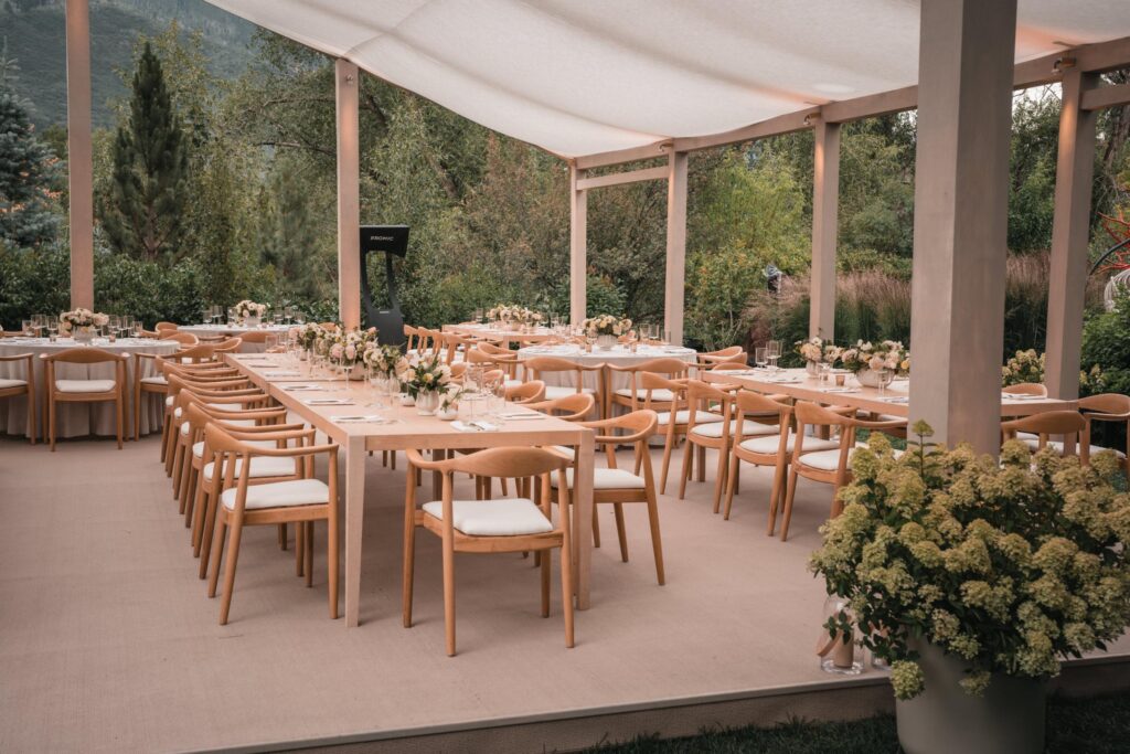 Long outdoor dinner table set beneath a tent with mountain views