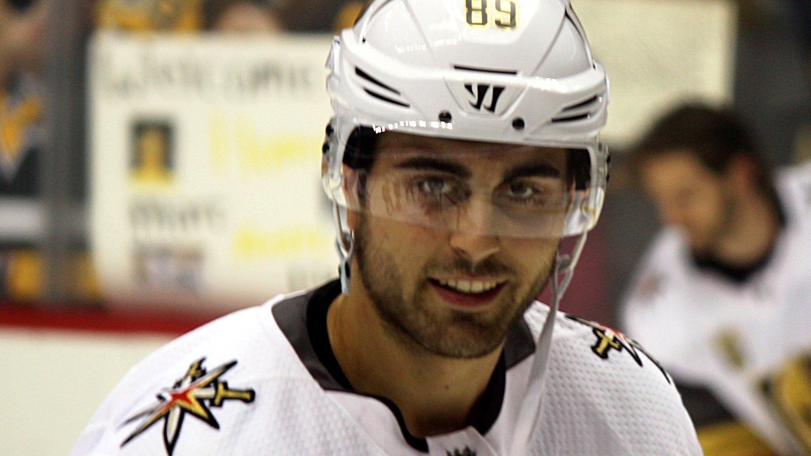 Alex Tuch smiling in a white helmet with a clear visor during warmups