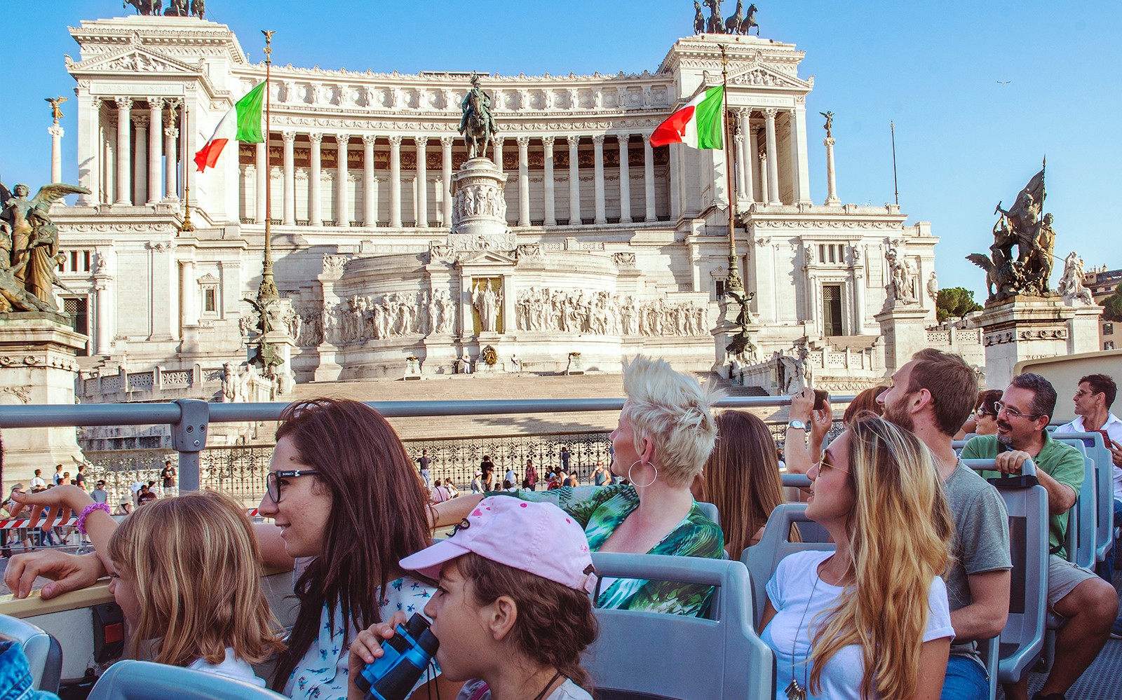 Tourists on a hop-on hop-off bus viewing the Altare della Patria in Rome.