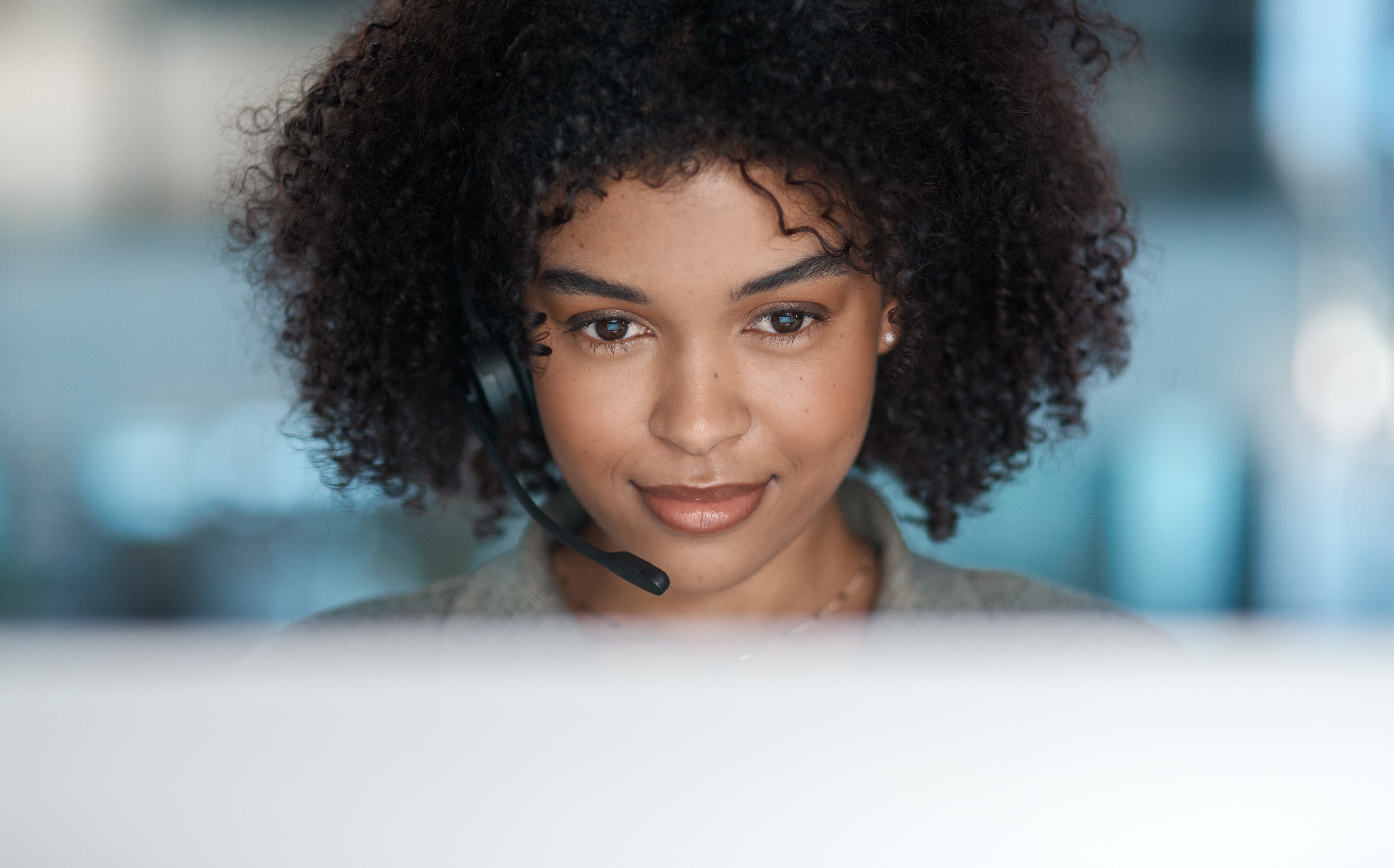 A contact-centre agent wearing a headset focuses on her computer screen.