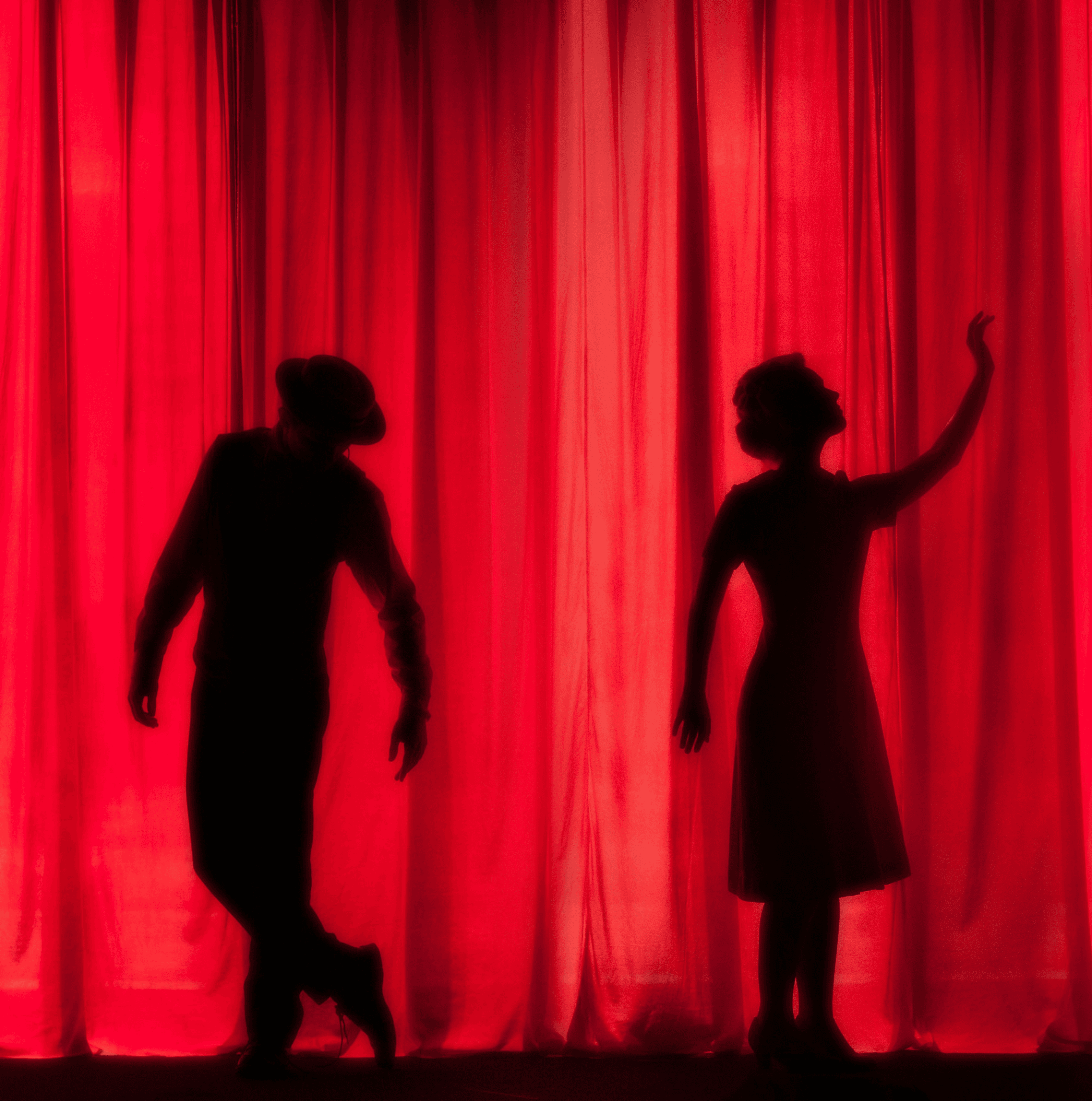 silhouette of three performers on stage