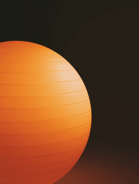 A close-up, high-contrast photograph of a large, textured sphere (resembling an exercise ball) positioned on the left side of the frame against a solid dark background.