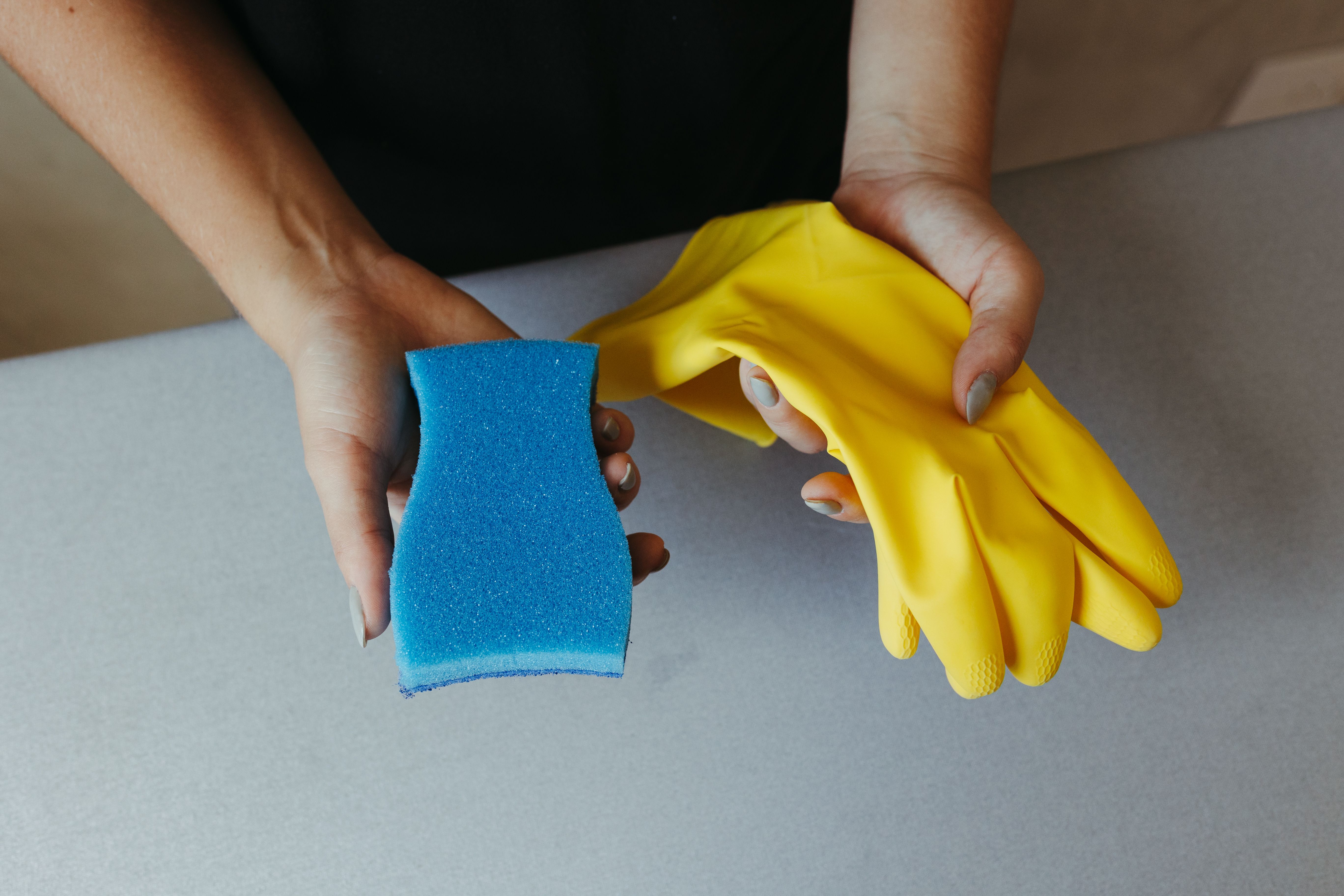 A person sorting old cleaning products from under the sink, deciding how to dispose of each one safely.