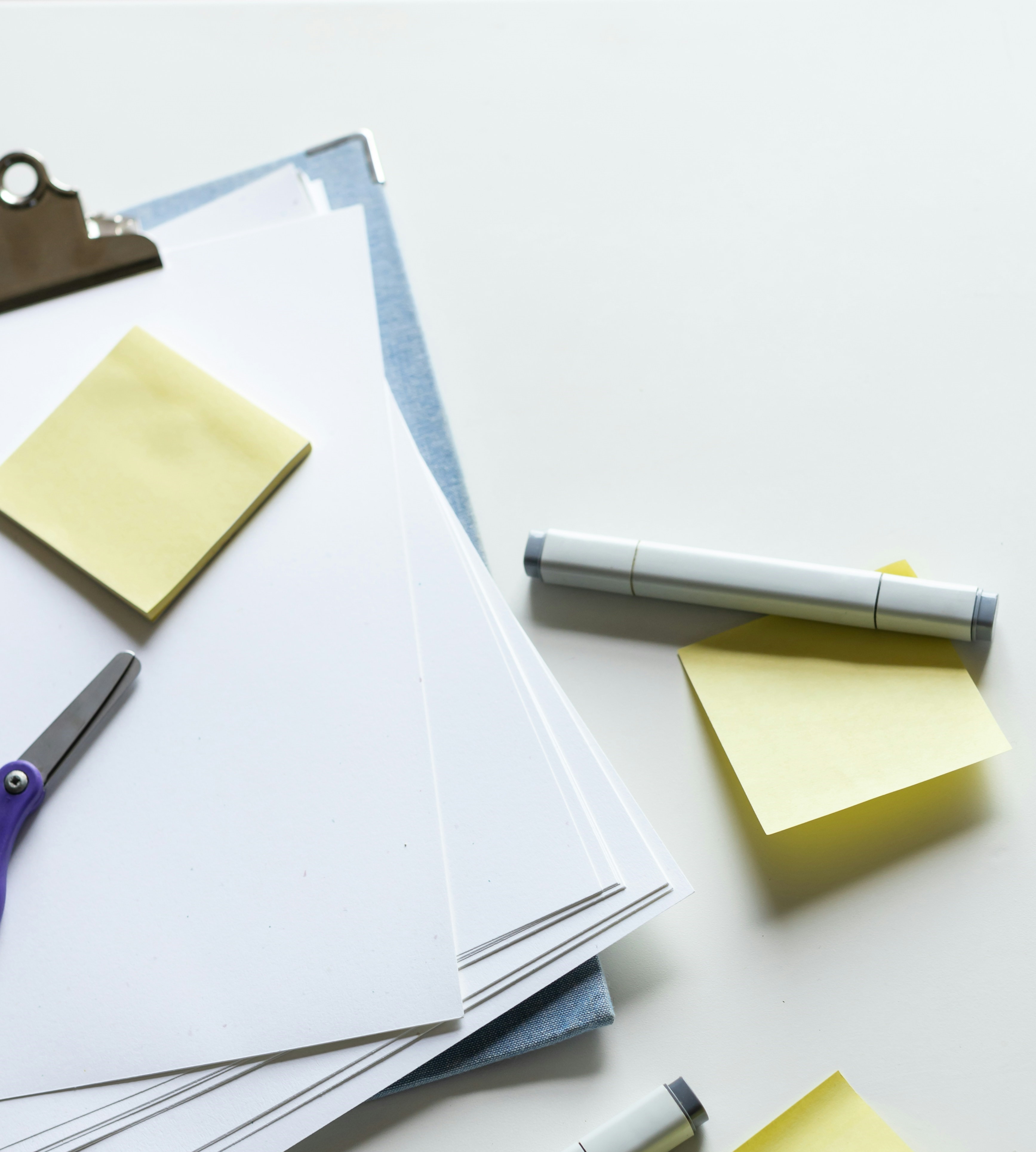Office supplies with blank sheets and sticky notes on a desk