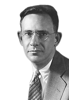 A black-and-white portrait of a man wearing round glasses, a suit, and a patterned tie. He has a serious, focused expression that conveys professionalism and intellectual depth, typical of early to mid-20th-century academic or scientific figures.