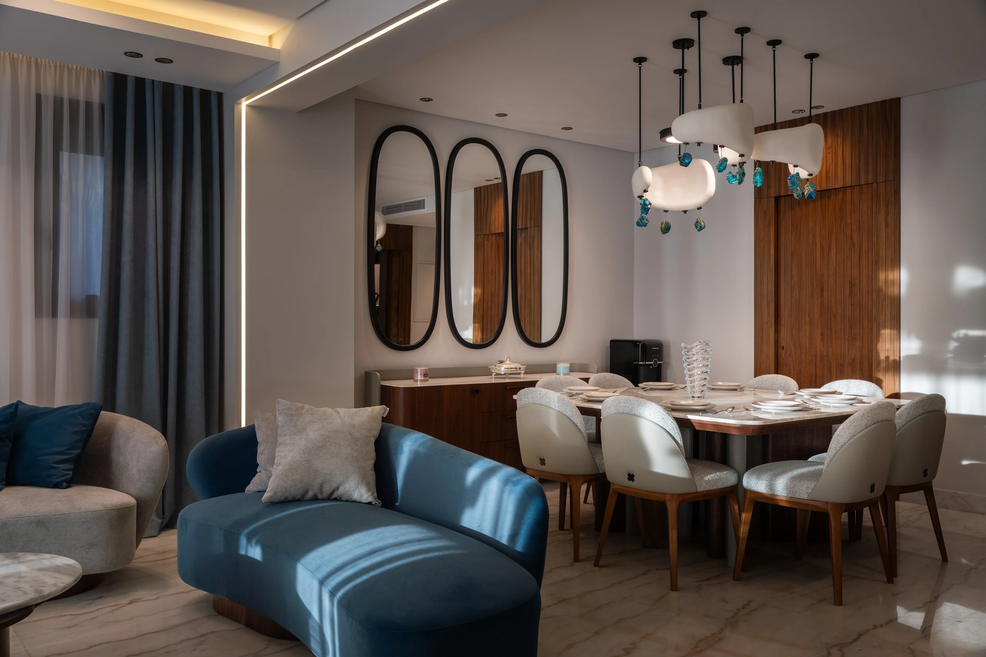 Mivida Twin Villa dining room with custom furniture, blue accents, walnut details, and mirrored wall panels.