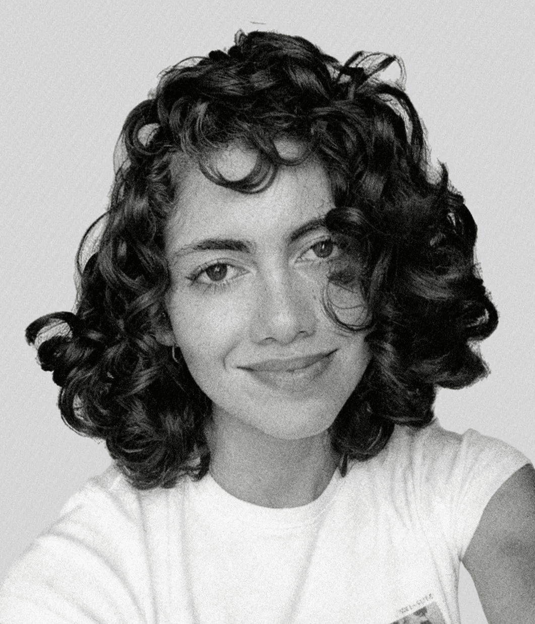 Portrait of a woman with straight long hair, in a dark t-shirt, set against a neutral backdrop.