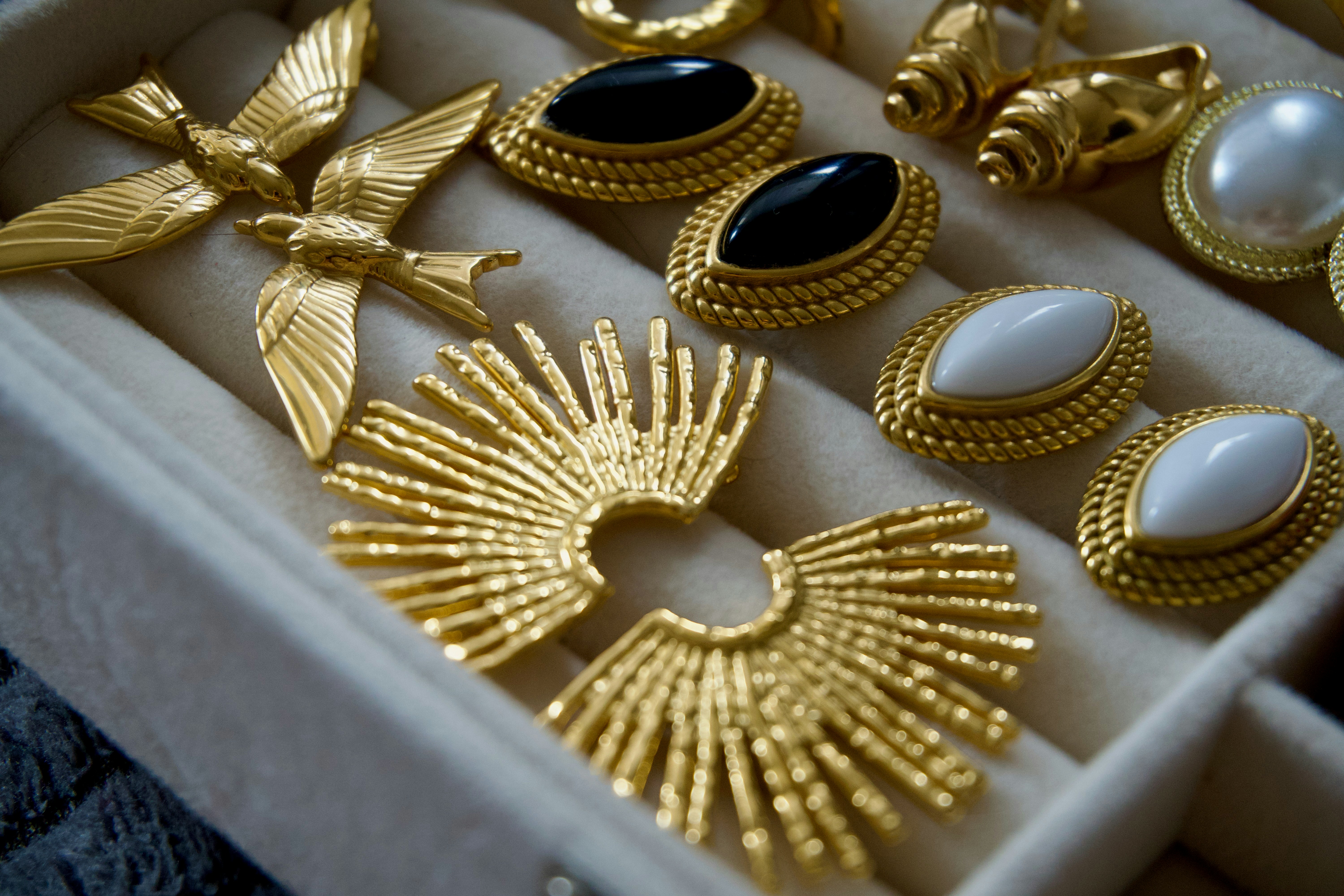 Antique gold jewellery arranged in a tray, showing brooches and earrings in a single metal tone