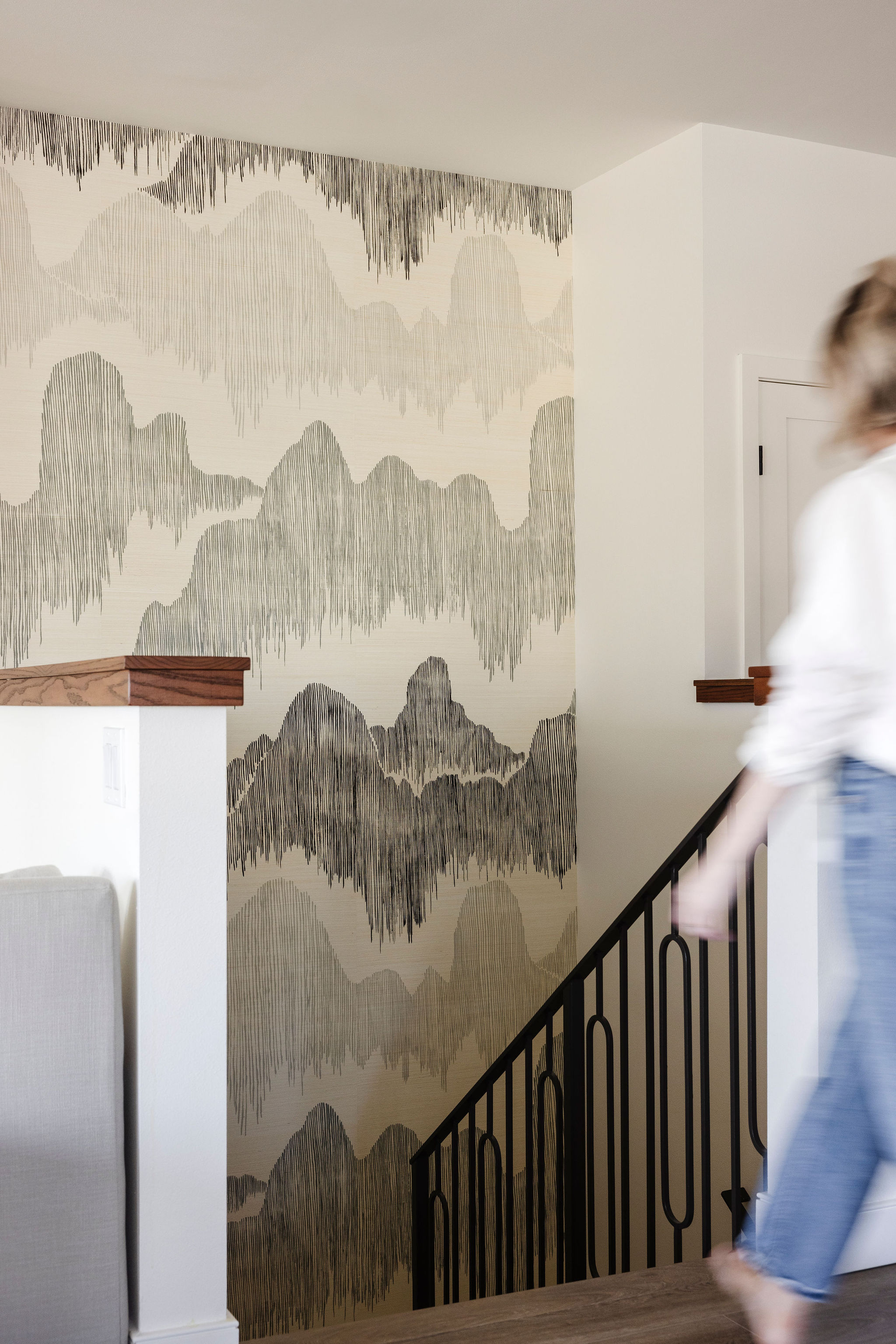 Beautiful staircase at highlighted by a statement wall with unique coastal-inspired wallpaper, paired with sleek railings and warm wood steps for a modern yet inviting design.