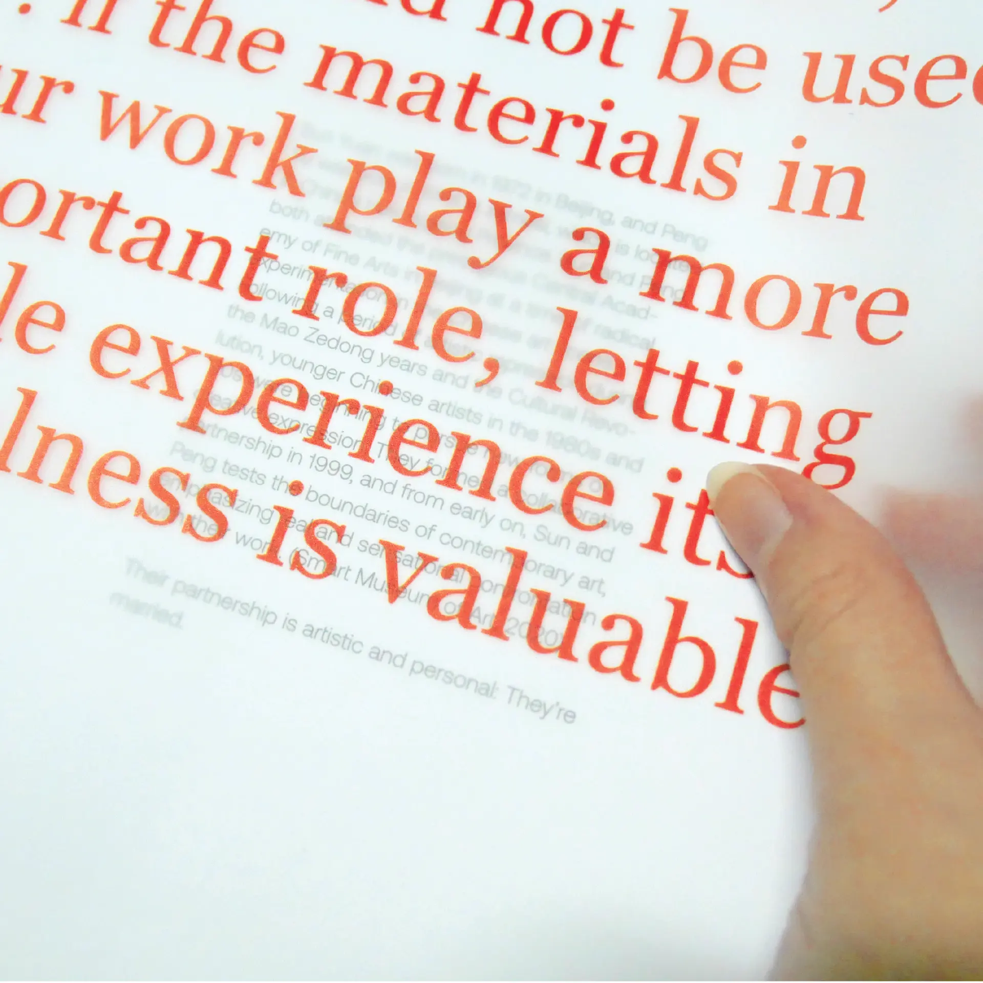 A hand between two pages, the first somewhat transparent and barely showing the one underneath
