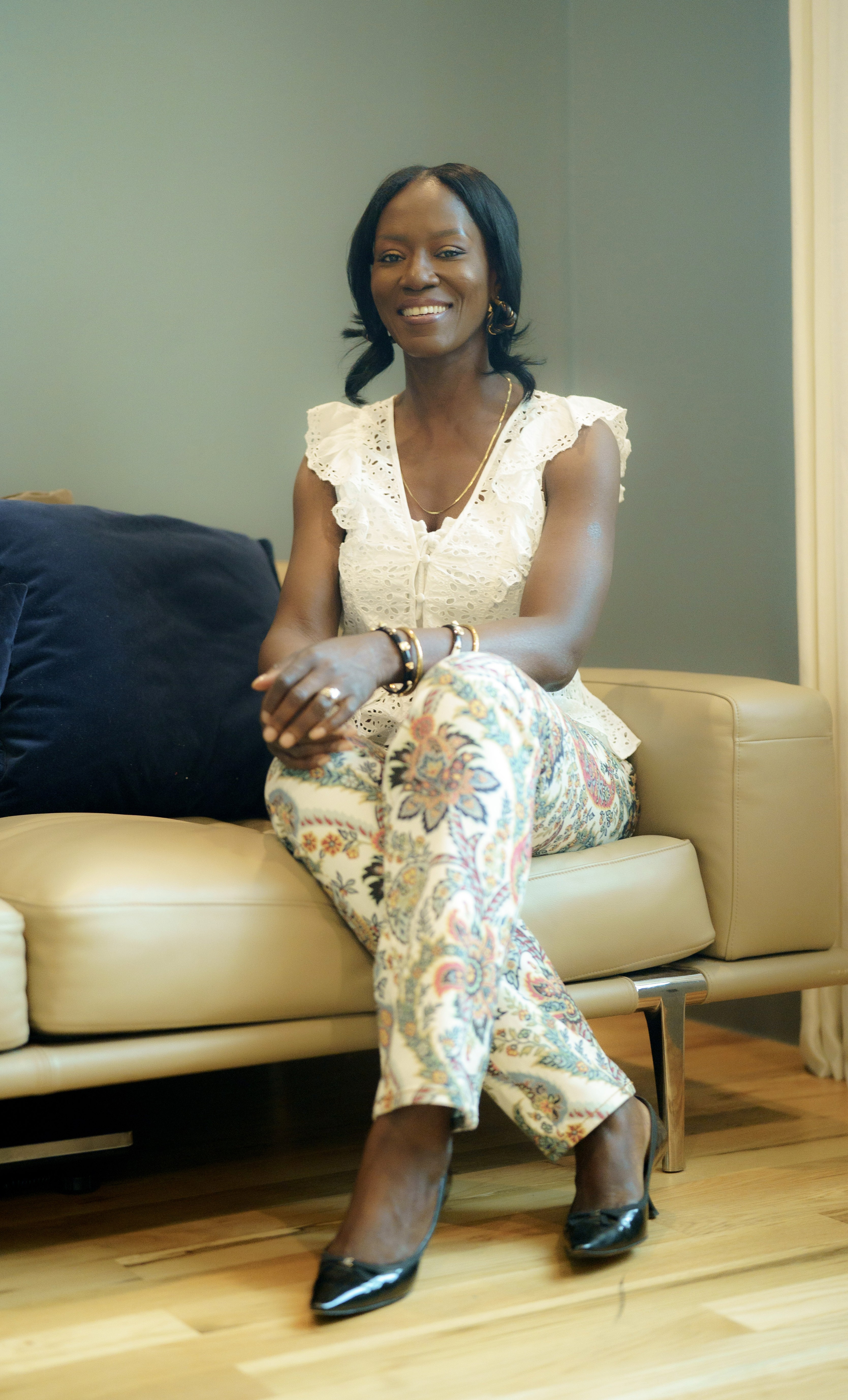 Woman in a light suit sitting thoughtfully against a terracotta wall