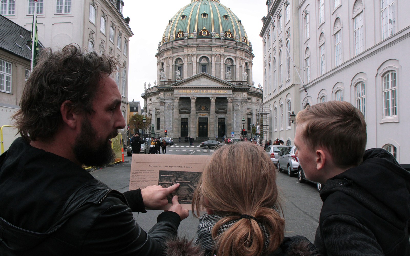 Participants in a mystery hunt near Amalienborg Palace, Copenhagen, examining a map.