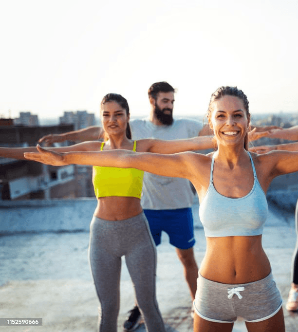 Group of individuals practicing outdoor yoga, promoting holistic well-being and  reimagining workplace environments to prioritize both mental and physical health.