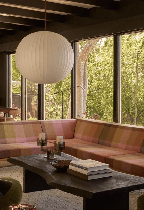 Pink curved sofa in a warm living room with large windows — The Warren project
