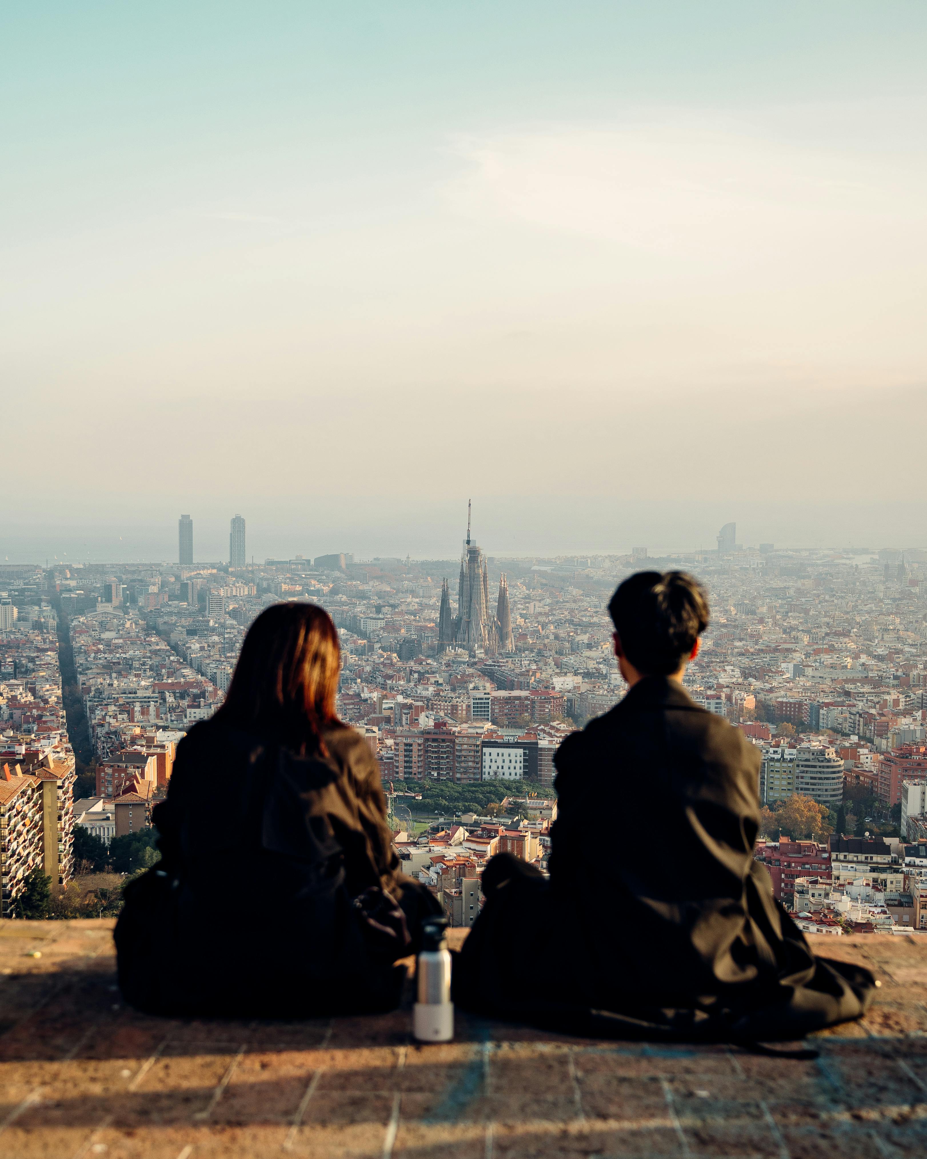 Twee mensen die naar de stad Barcelona kijken vanaf Los Bunkers, met een prachtig panoramisch uitzicht.