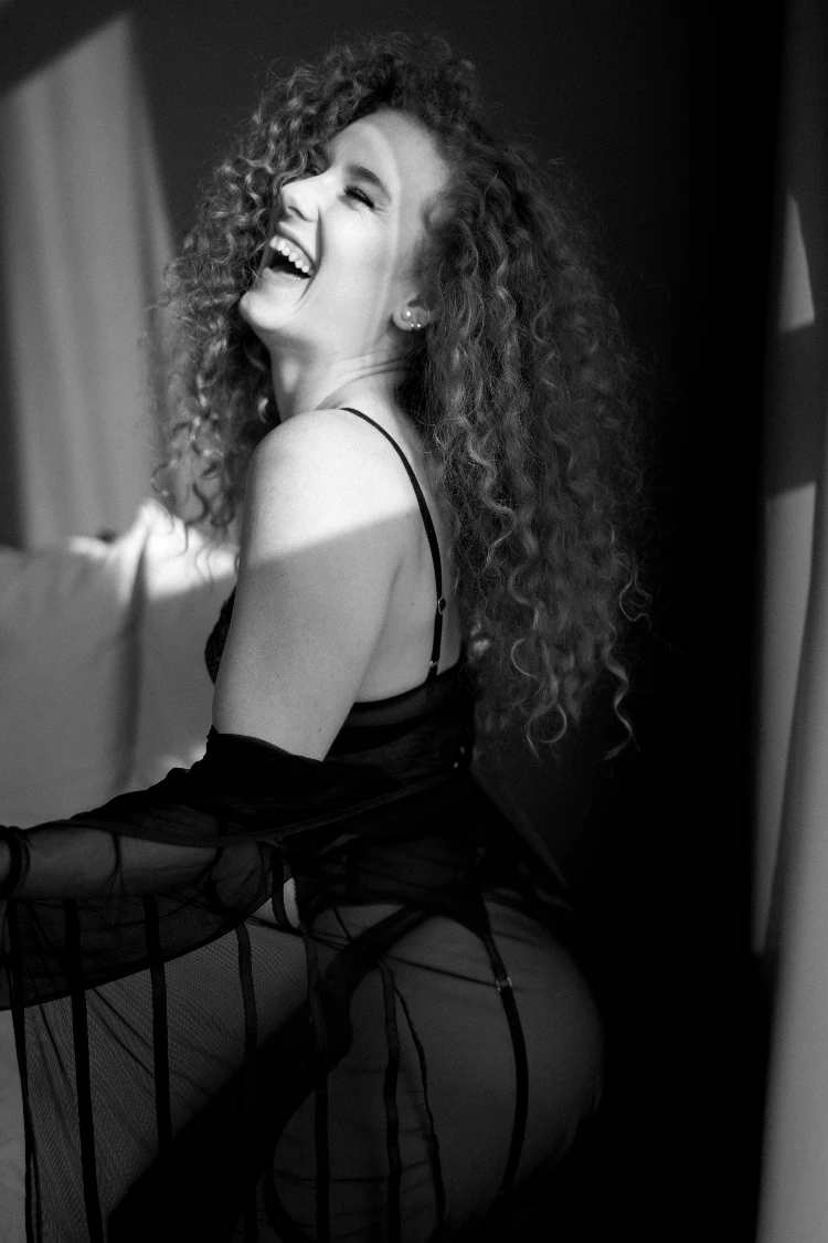 Laughing woman in black attire; a sensual boudoir art experience in Solothurn.