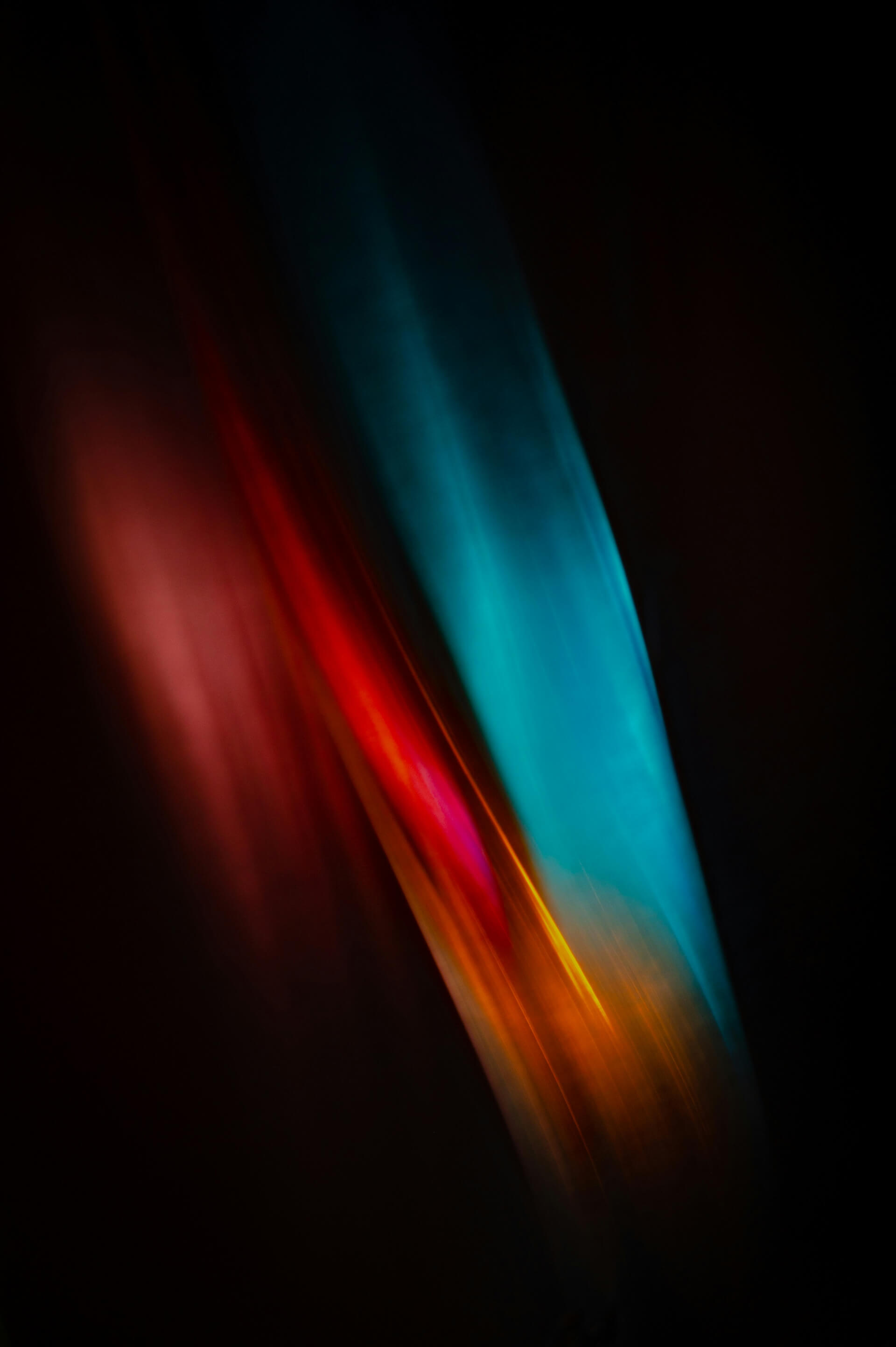 This image features an abstract composition with dynamic, colorful light streaks. The visual includes:  A bright cyan-blue vertical streak toward the right.  A red to orange gradient streak intersecting the blue one from the left.  Deep black and dark maroon tones in the background, giving a strong contrast.  The effect suggests motion blur or light painting, commonly achieved through long exposure photography.  It conveys a sense of energy and fluidity, and could easily be interpreted as digital art or a stylized light abstraction.