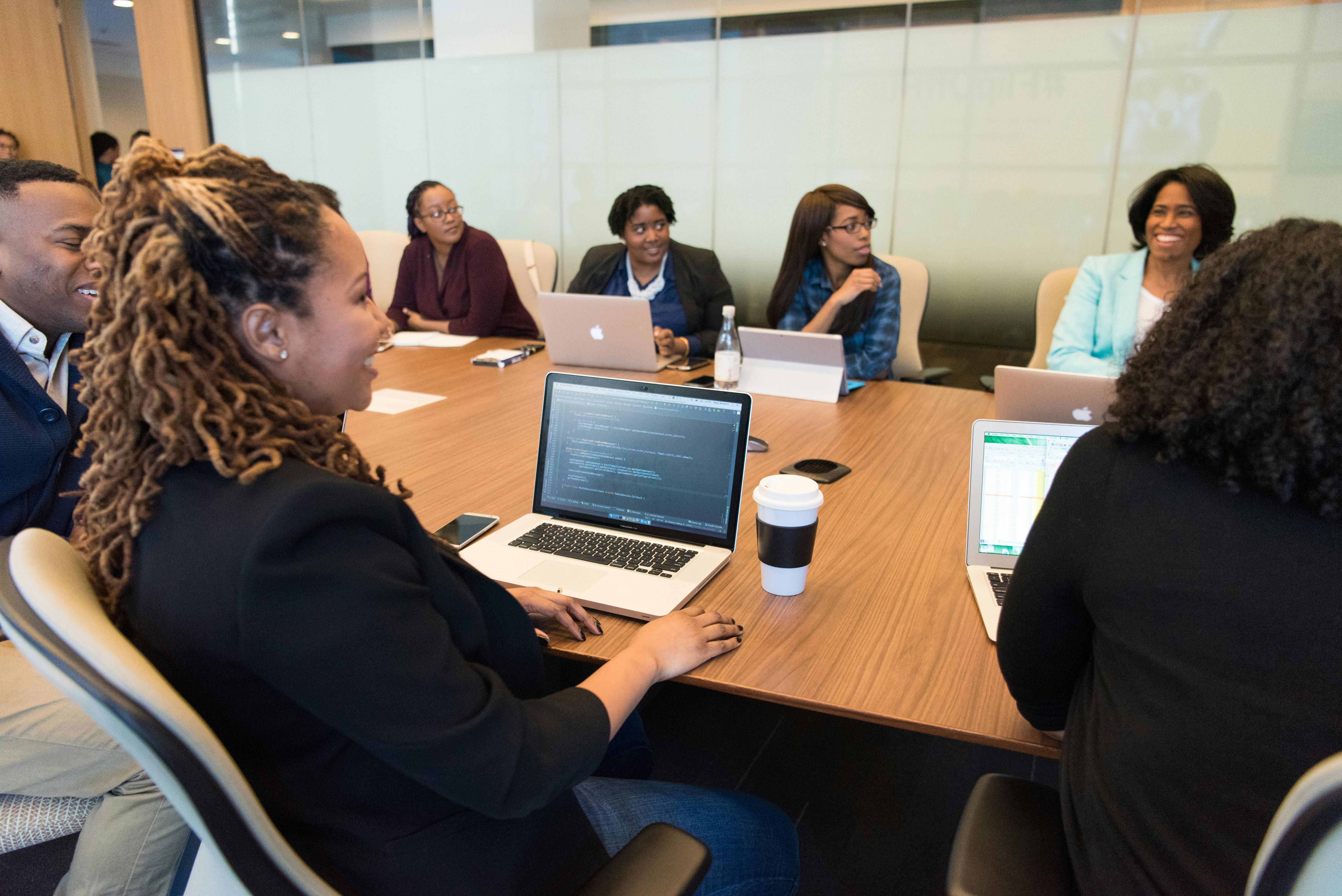 people sitting on chair in front of table while holding pens during daytime