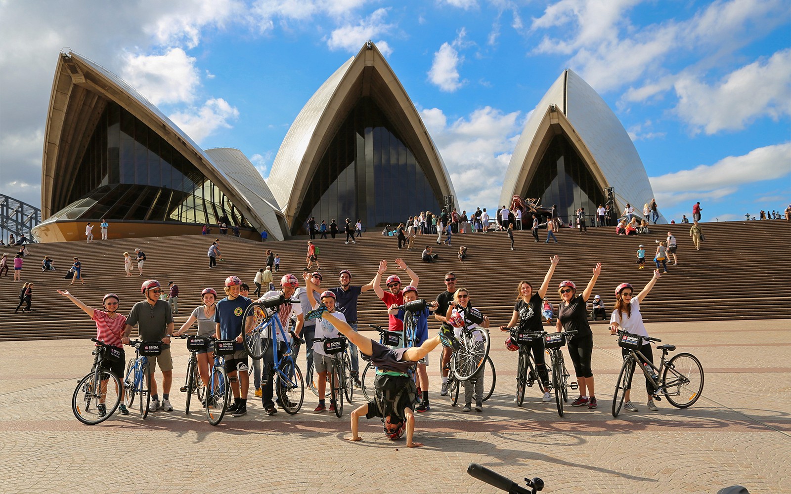 Gruppo di ciclisti che posa con biciclette davanti alla Sydney Opera House.