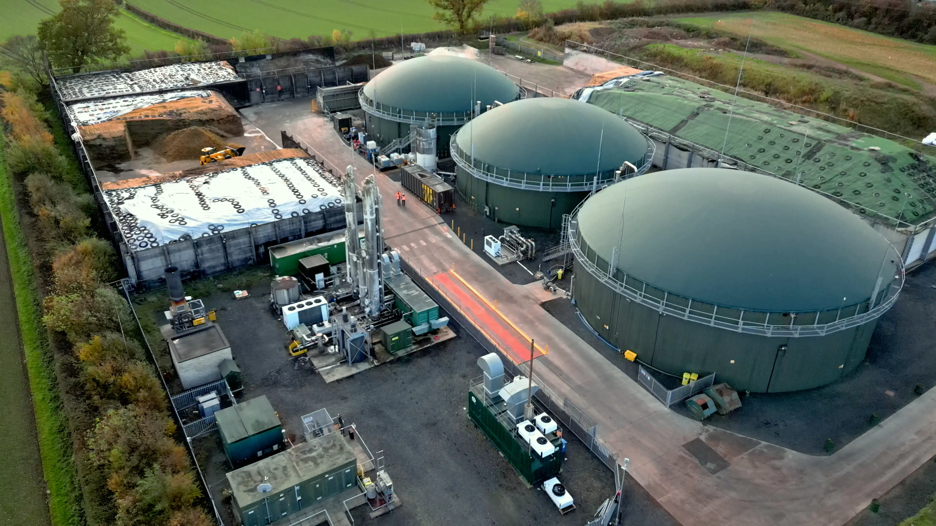 A bright blue Scania truck with "BLACKS" branding drives through an industrial area. Nearby, there are large black and white shipping containers.