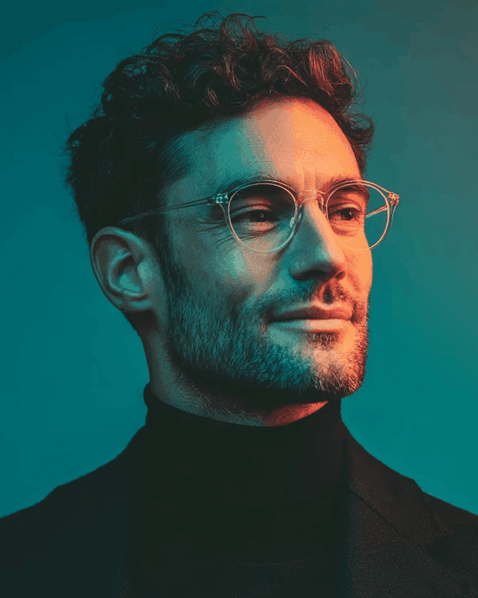 Man with curly hair and glasses portrait with teal lighting