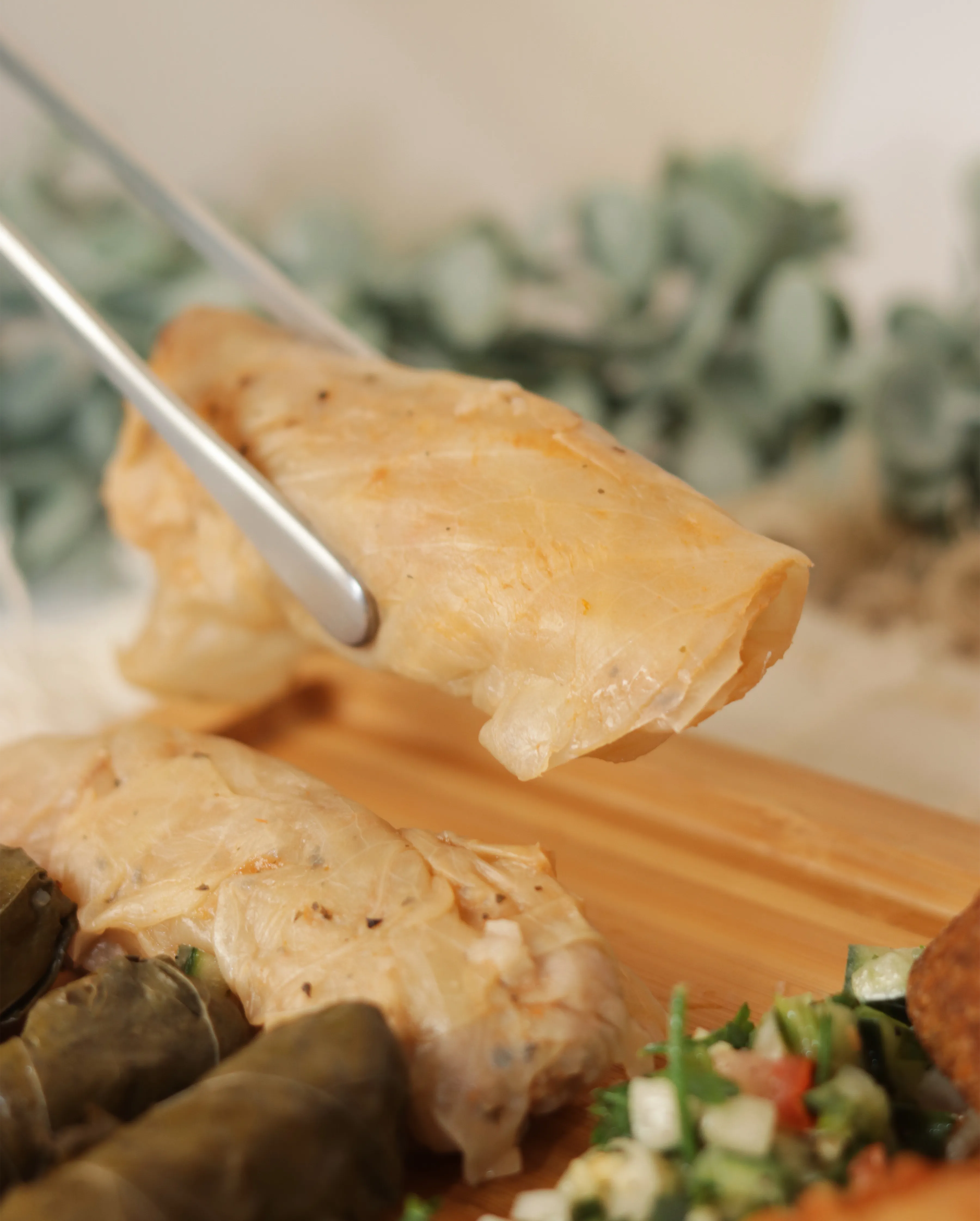 Hoja de parra rellena de arroz servida con pinzas.