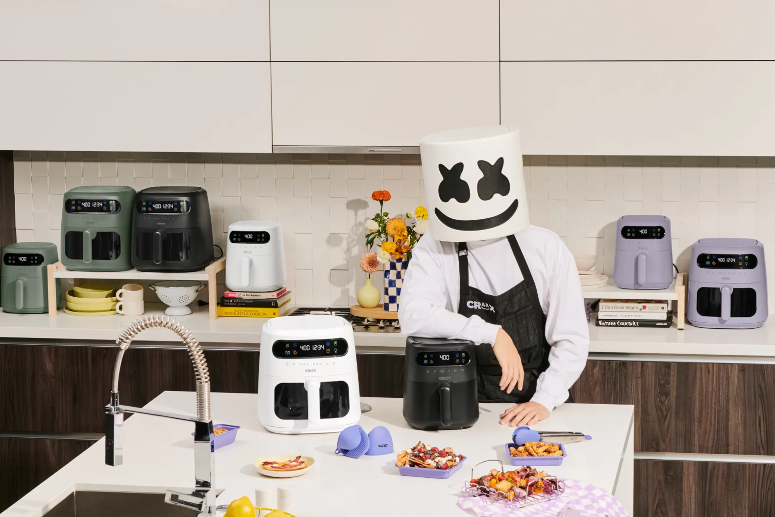 A person in a marshmallow costume stands in a kitchen, surrounded by cooking appliances and ingredients.