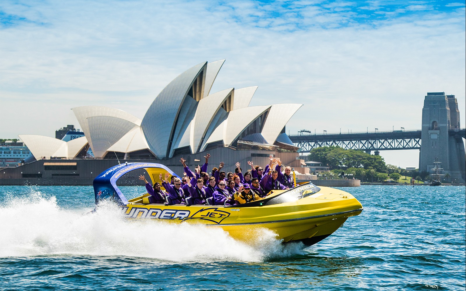 Jet boat con passeggeri vicino alla Sydney Opera House e al Ponte del Porto.