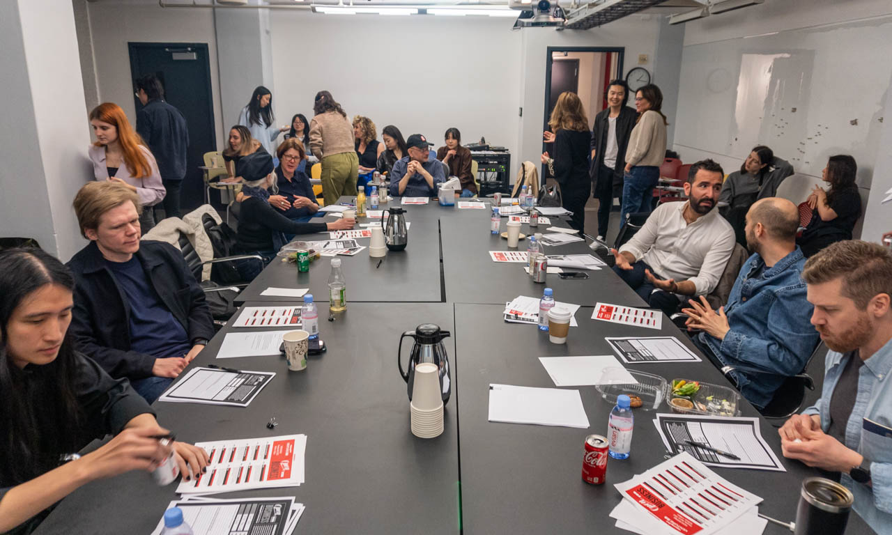 a large group of people sitting around a series of tables at a meeting
