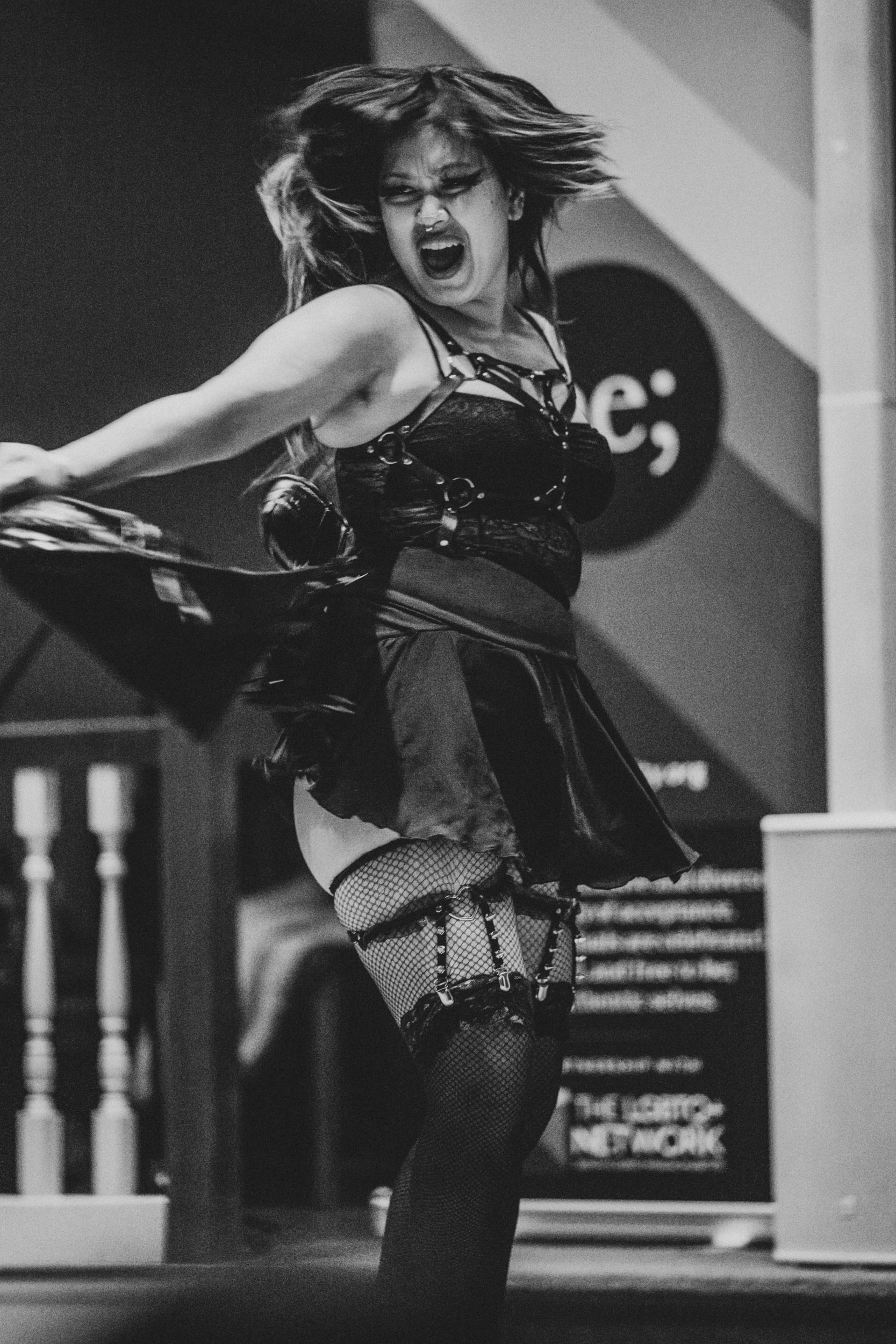 Performer dancing energetically on stage at Queer Open Mic hosted by be; community in Bridgewater, Massachusetts