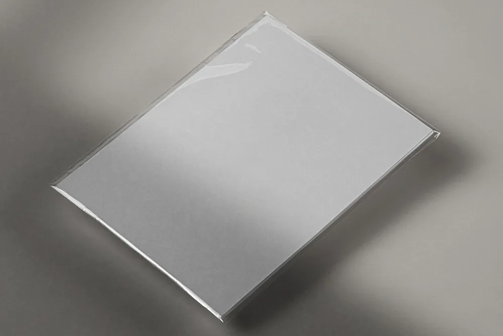 Booklet or catalog mockup encased in a transparent cellophane wrapper, featuring a modern design with abstract gradient graphics in blue and purple. Displayed on a dark surface with soft lighting and reflections.