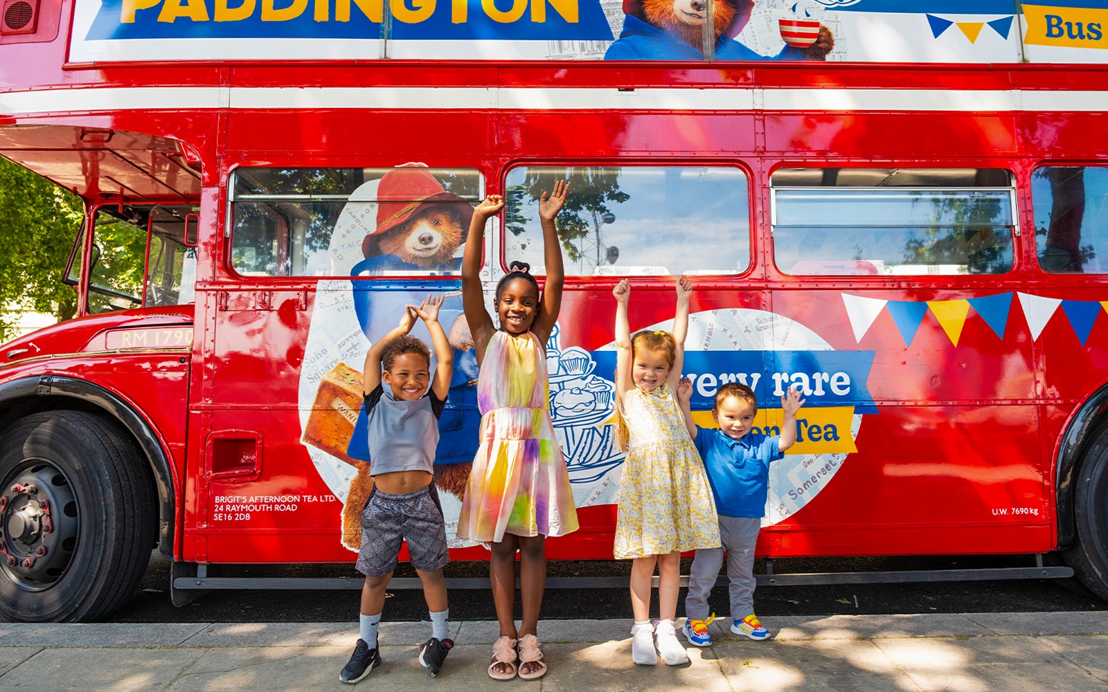 Children posing in front of the Paddington Afternoon Tea Bus in London.
