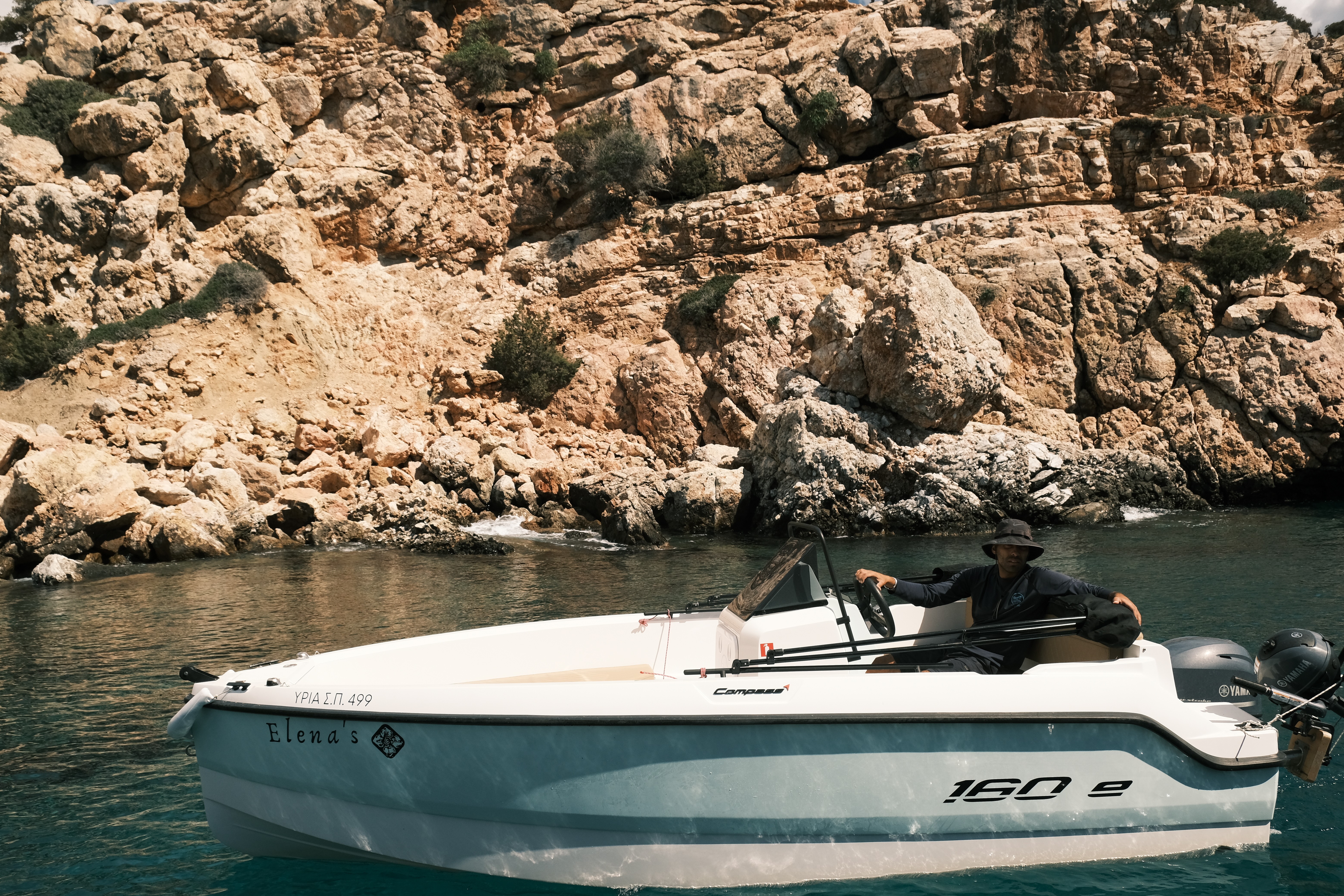Compass 16Oe yacht "Elena's" anchored in turquoise waters beside dramatic limestone cliffs in the Cyclades.