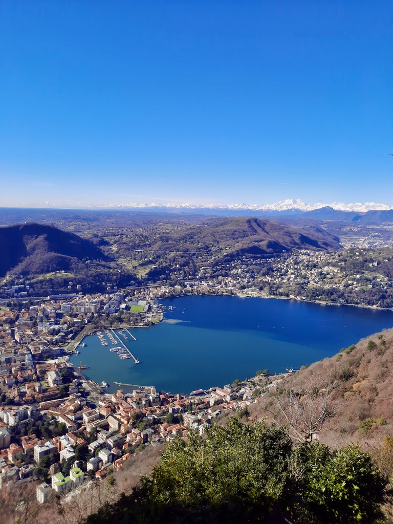 Lake Como and the city of Como seen from Brunate, with clear sky that makes the mountain range behind seen.