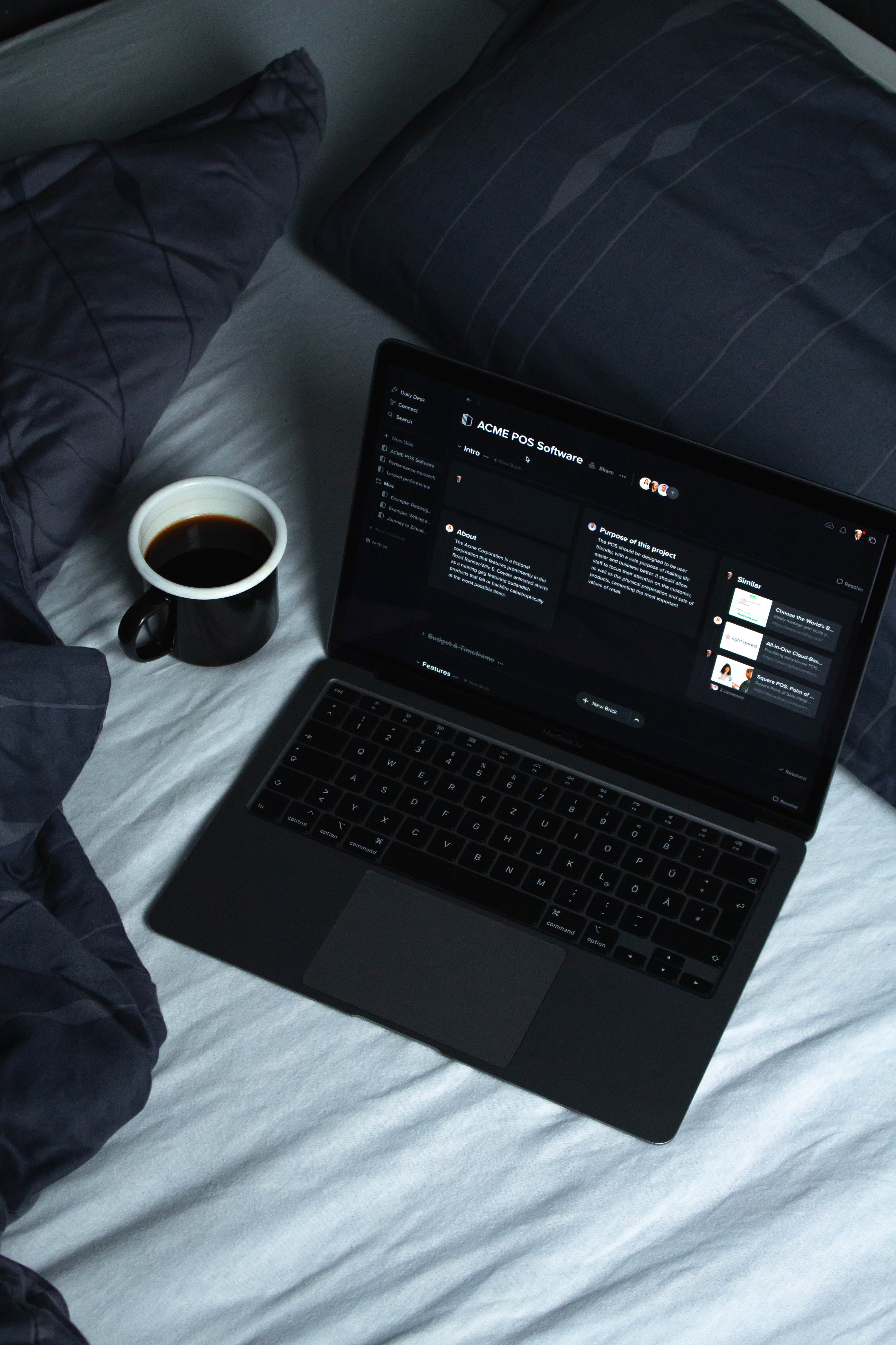 A laptop and coffee cup on a bed