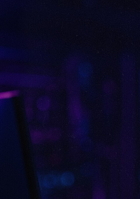 Creative tech worker in a cyberpunk setting with bi-directional blue and purple light against a blurred background.